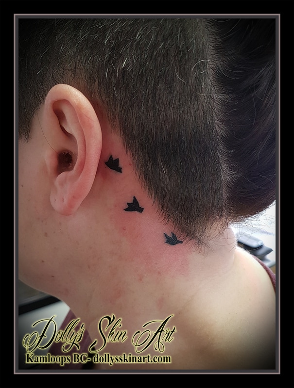 3 small black birds flying behind ear hairline tattoo kamloops dolly's skin art
