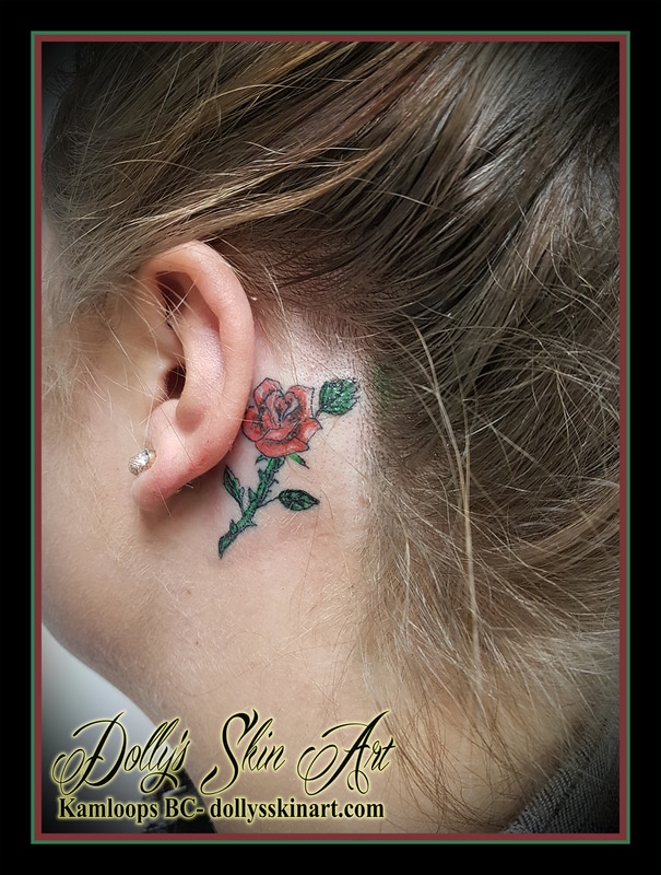 cute little red and green colour rose flower tattoo behind ear small kamloops dolly's skin art