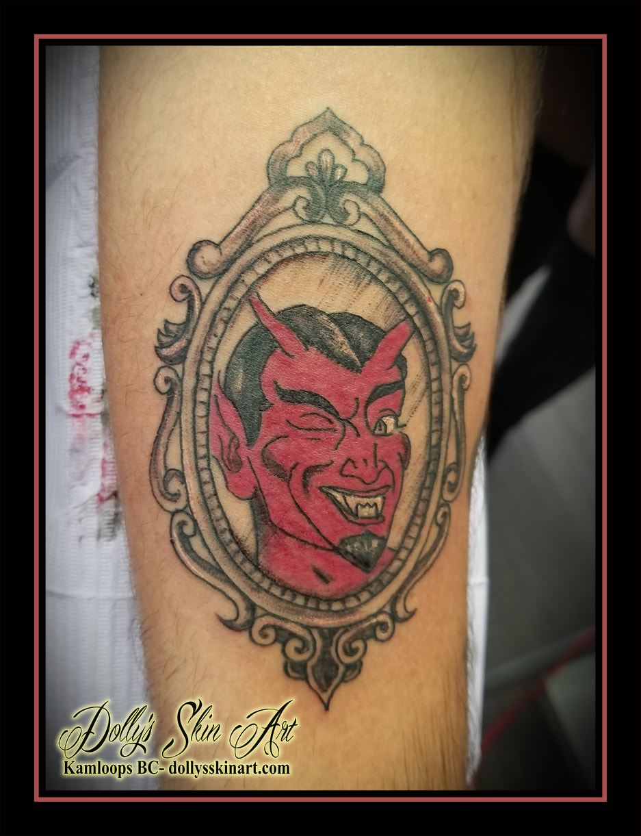 devil portrait wink traditional style frame black and grey red shading forearm tattoo dolly's skin art kamloops
