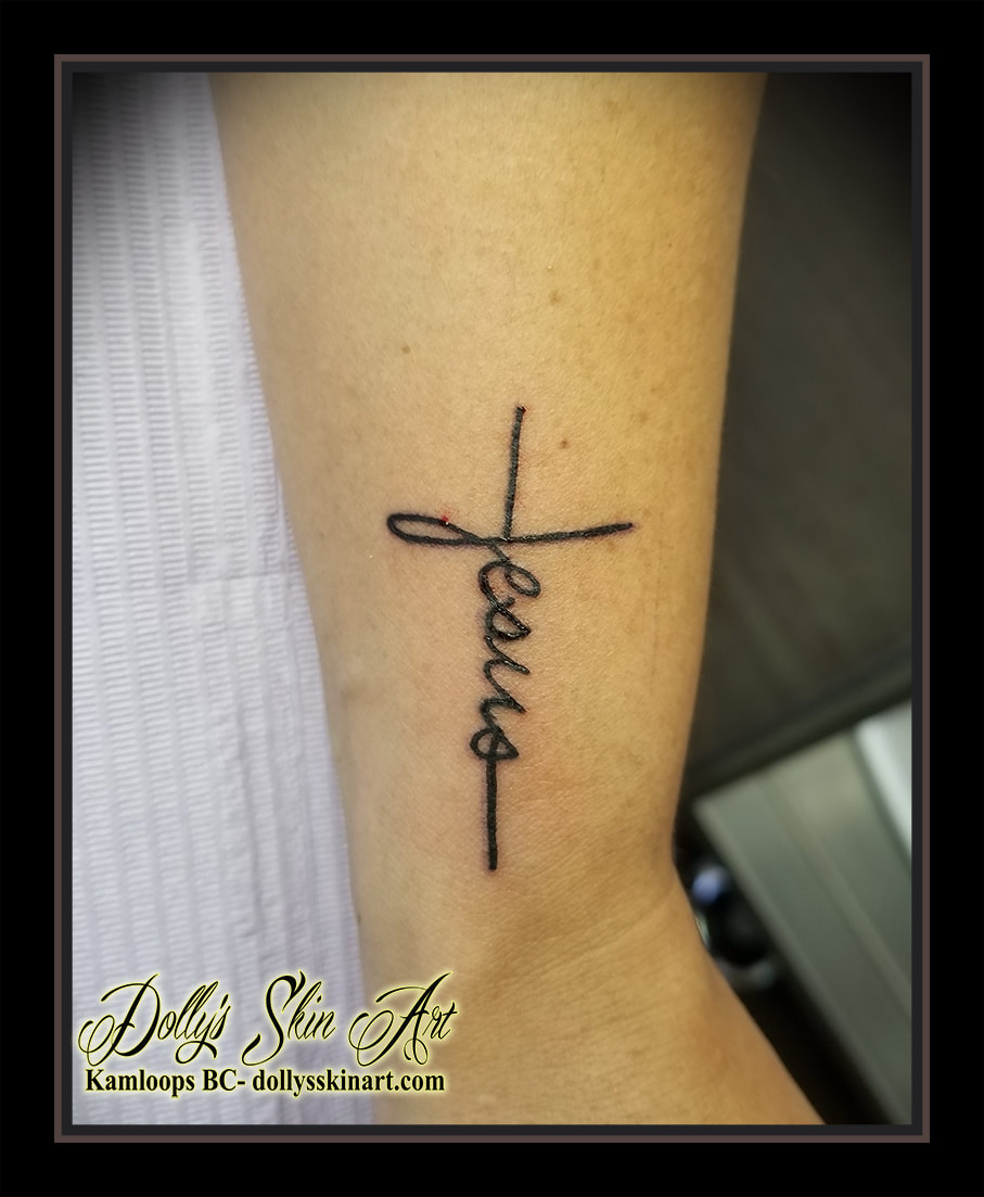 small black cross jesus simple line work wrist forearm tattoo kamloops tattoo dolly's skin art