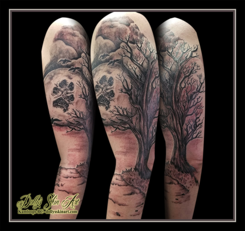 black and grey tattoo tree moon scene trail paw print arm shoulder sky clouds tattoo kamloops dolly's skin art